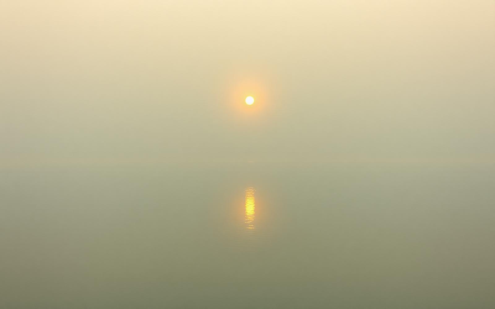 Kalme wateroppervlakte bij zonsopkomst